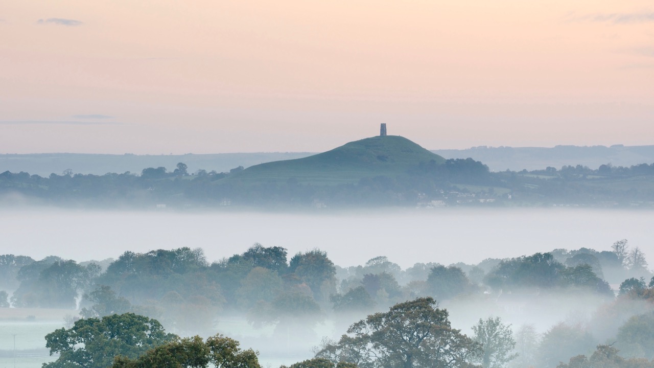 Mist shrouded fields leading towards Glastonbury Tor which dominates the flat landscape of the surrounding Somerset Levels.